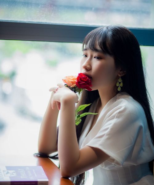 Person sitting in a lotus pose near a window, looking serene and enlightened.